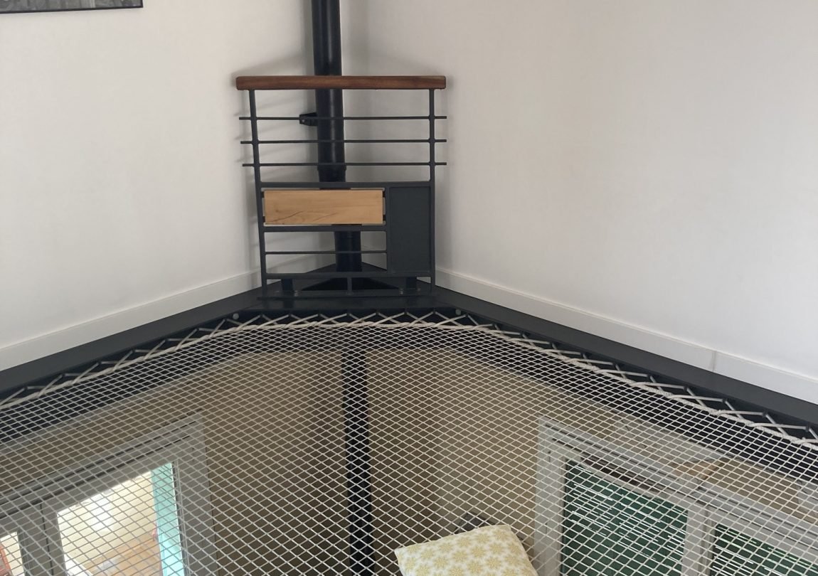 Photo d'un garde-corps en bois et en métal protégeant l'accès à un conduit de poêle à granulé